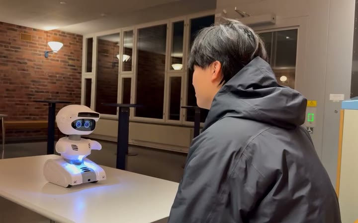 A Misty II robot on a table turning towards a person standing beside it.
